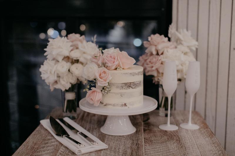 Real bride Nicole's white wedding cake with blush and white florals decorating it made by Art of Baking.