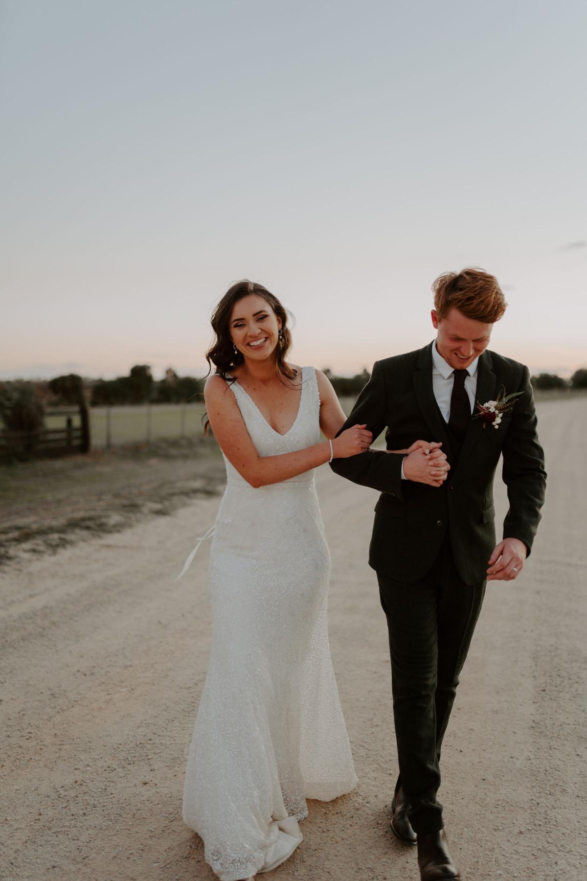 KWH real bride Amber walks with new husband Stewart while wearing the beaded Olympia gown with v-neck.