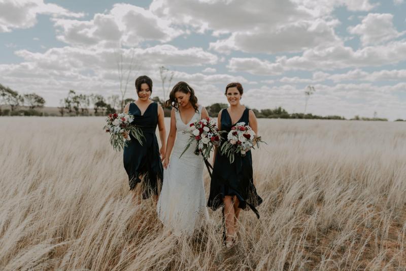 KWH real bride Amber with her bridesmaids in a field. She wears the all beaded Olympia wedding dress with v-back and neckline.
