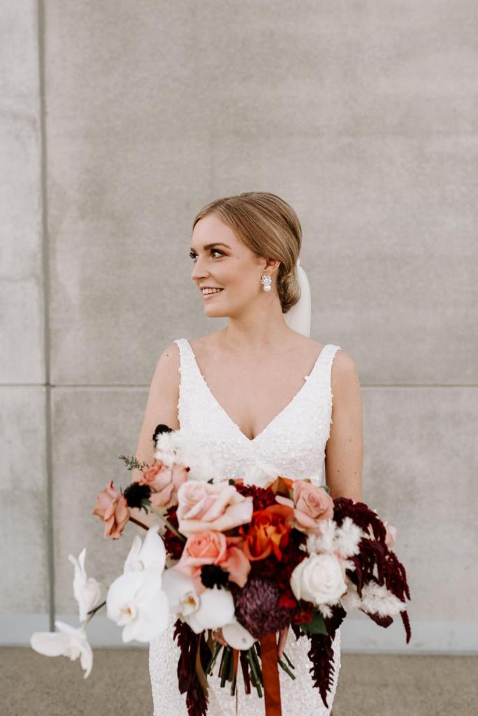 KWH real bride Katie holds her autumn inspired bouquet by Bits and Buds. She wears the stunning v-neck Lola wedding dress.