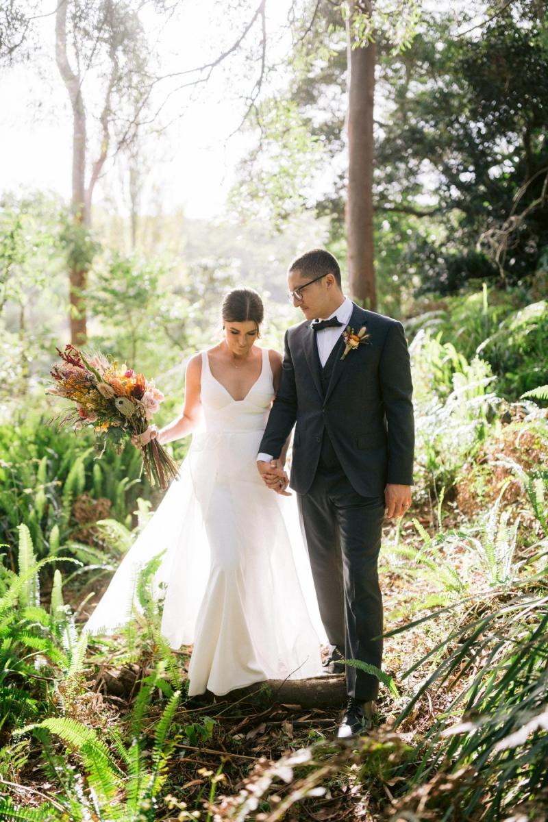 KWH real bride Annalese wears her Aisha gown with see through aline skirt in the woods with her new husband.