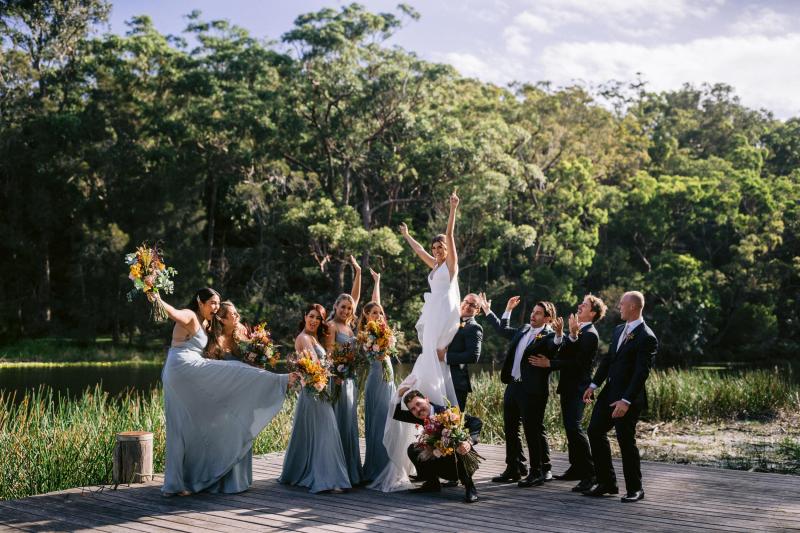 KWH real bride Annalese celebrates with her wedding party as they jump for joy. She wears the flowy Aisha gown with aline skirt.