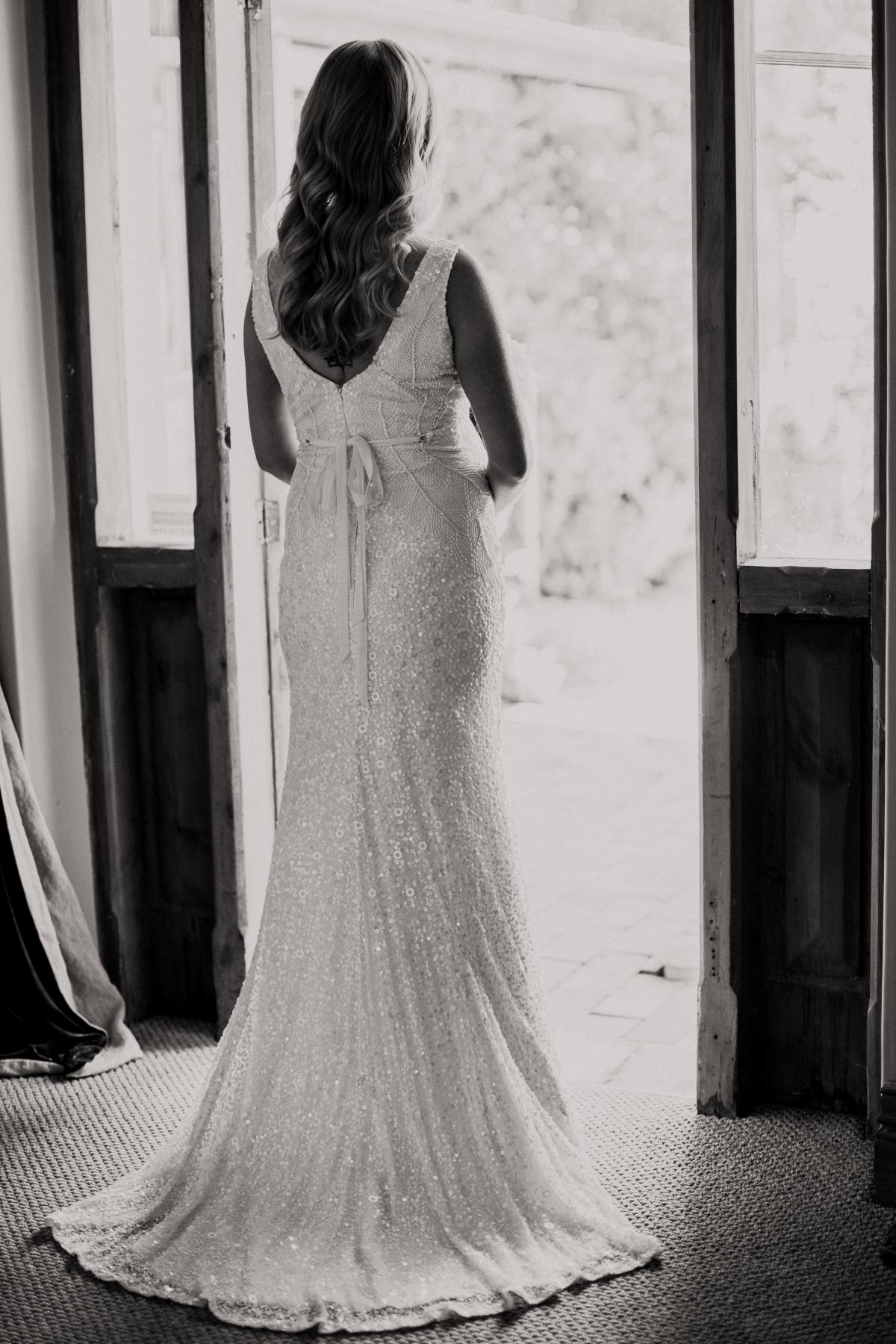 KWH real bride standing in the doorway in her beaded Olympia wedding dress with matching belt