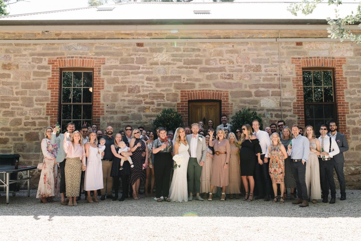 KWH real bride Bec and Nick stand with family and friends. She wears the classic Olympia wedding dress.