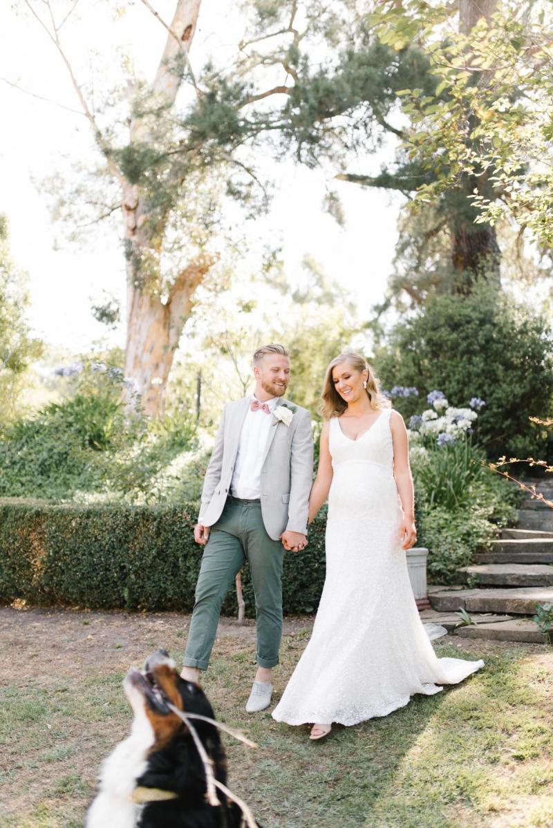 KWH real bride Bec and Nick walk around hand and hand with their dog in the front. She wears the classic Olympia wedding dress with sequin and beads.