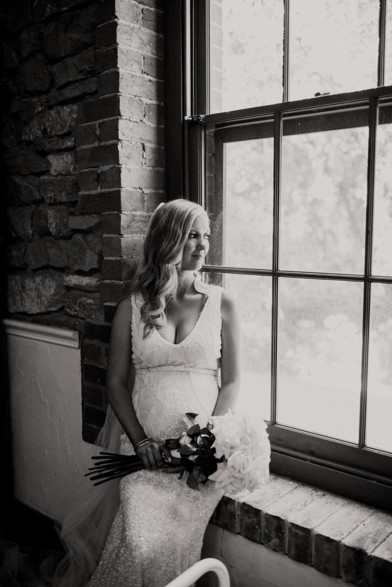 KWH real bride Bec sits in front of a window. She wears the fit and flare Olympia gown.