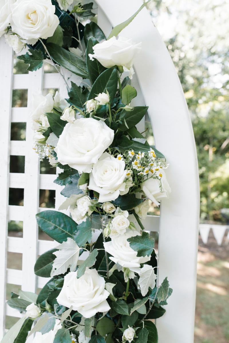 White roses with green leaves on a white lattice arbour at KWH real bride Bec's wedding