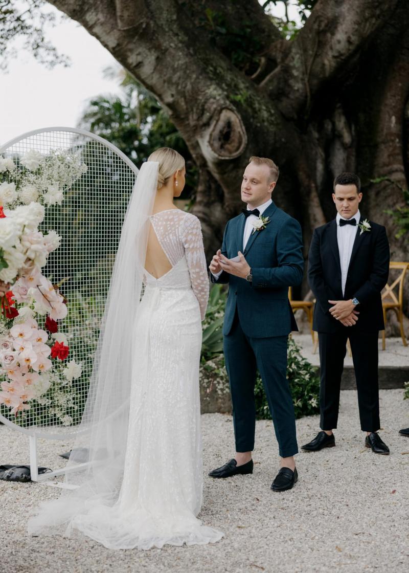 KWH real bride Taylor and Kalen standing in front of their circular wedding alter. She wears the ivory beaded Lexie gown.