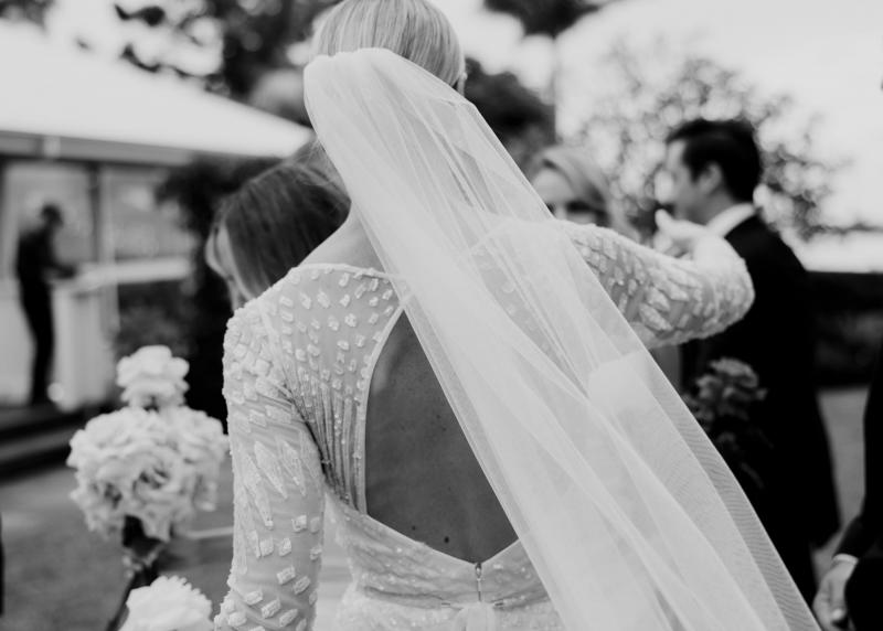 KWH real bride Taylor walking in her sweetheart neckline Lexie wedding dress with a drink in her hand.