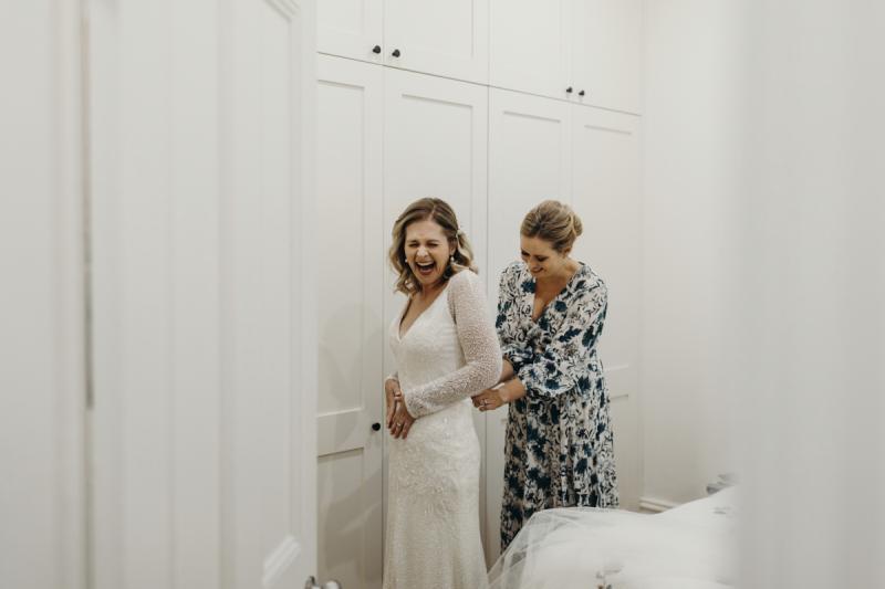 KWH real bride Emily gets ready by putting on her long sleeve Celine wedding dress with beaded details