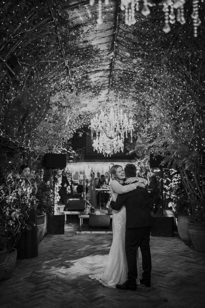 KWH real bride Emily and Mark dance under the chandelier. She wears the classic Celine wedding dress with fitted body shape.