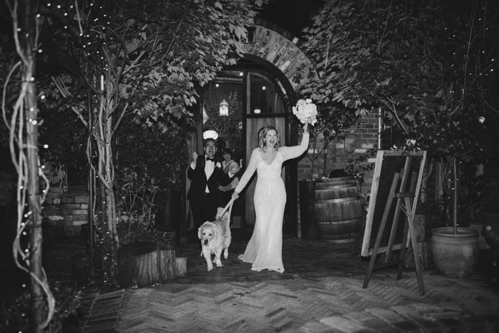 KWH real bride Emily coming into the reception with her dog by her side. She wears the effortless Celine wedding dress with beaded details.