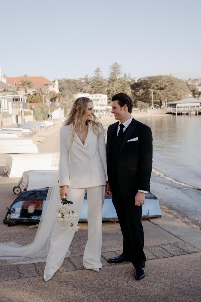KWH real bride Demi and James stand on the shore. She wears the sleek Charlie Danielle bridal suit with wide leg for her modern elopement.
