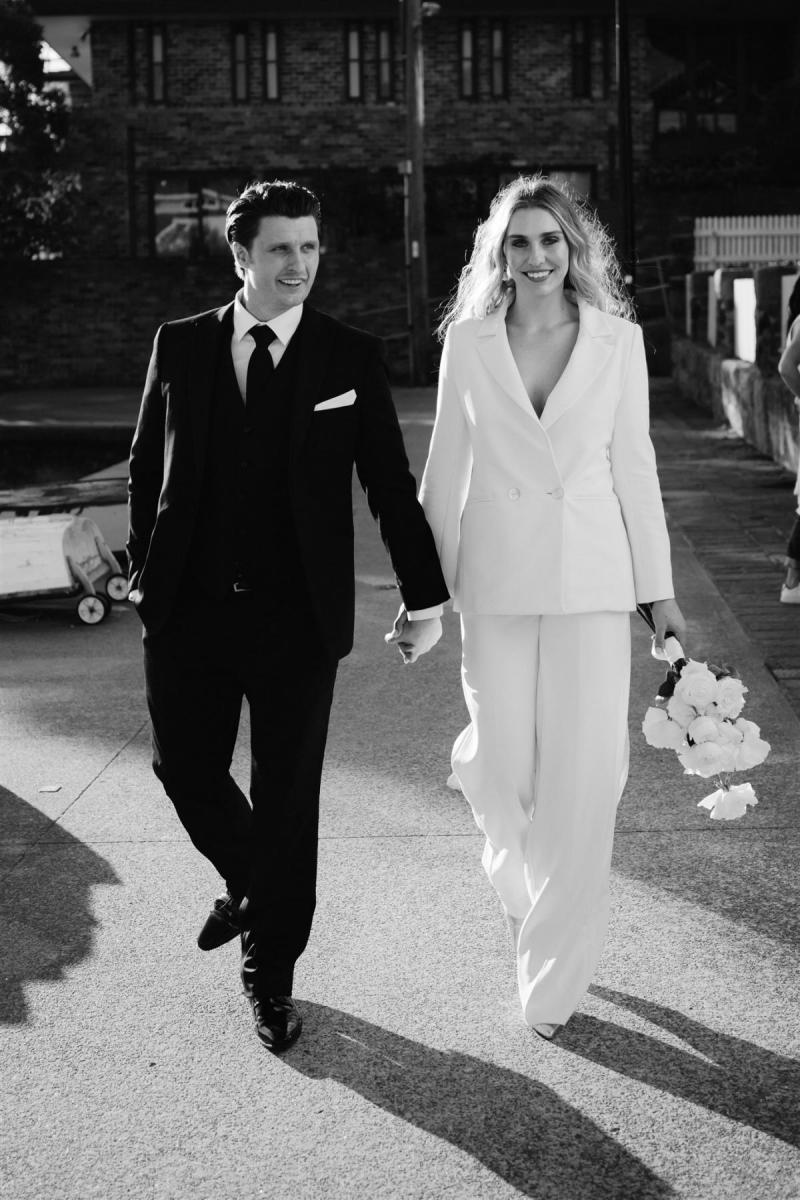 KWH real bride Demi and James walk down the street in their suits. Demi wears the Charlie Danielle bridal suit.