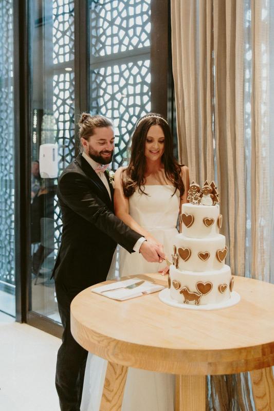 KWH real bride Libby and Luke cut their gingerbread cake. She wore the classic Esther wedding dress which is strapless and aline.