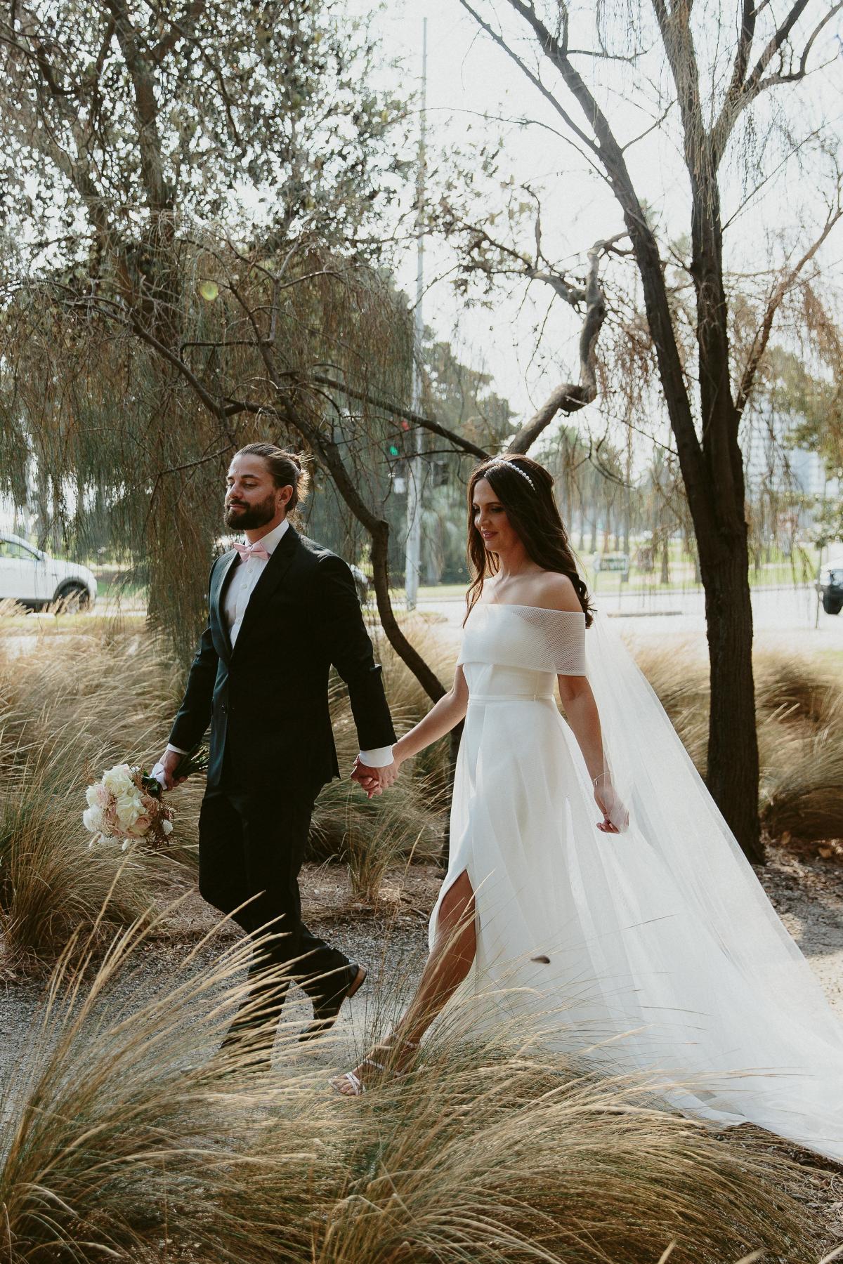 KWH real bride Libby walks with Luke through the woods. She wears the effortless Esther wedding dress with aline skirt and strapless bodice.