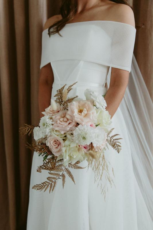KWH real bride Libby holding her bridal bouquet as she wears the stunningly simple Esther wedding dress with pleat details.
