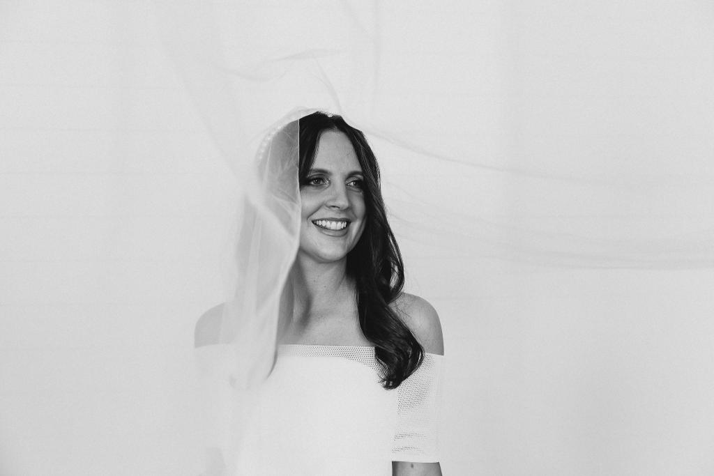 B&W portrait of KWH real bride Libby wearing her elegant Esther wedding dress with her long veil. The dress features a detachable mesh collar and strapless bodice.