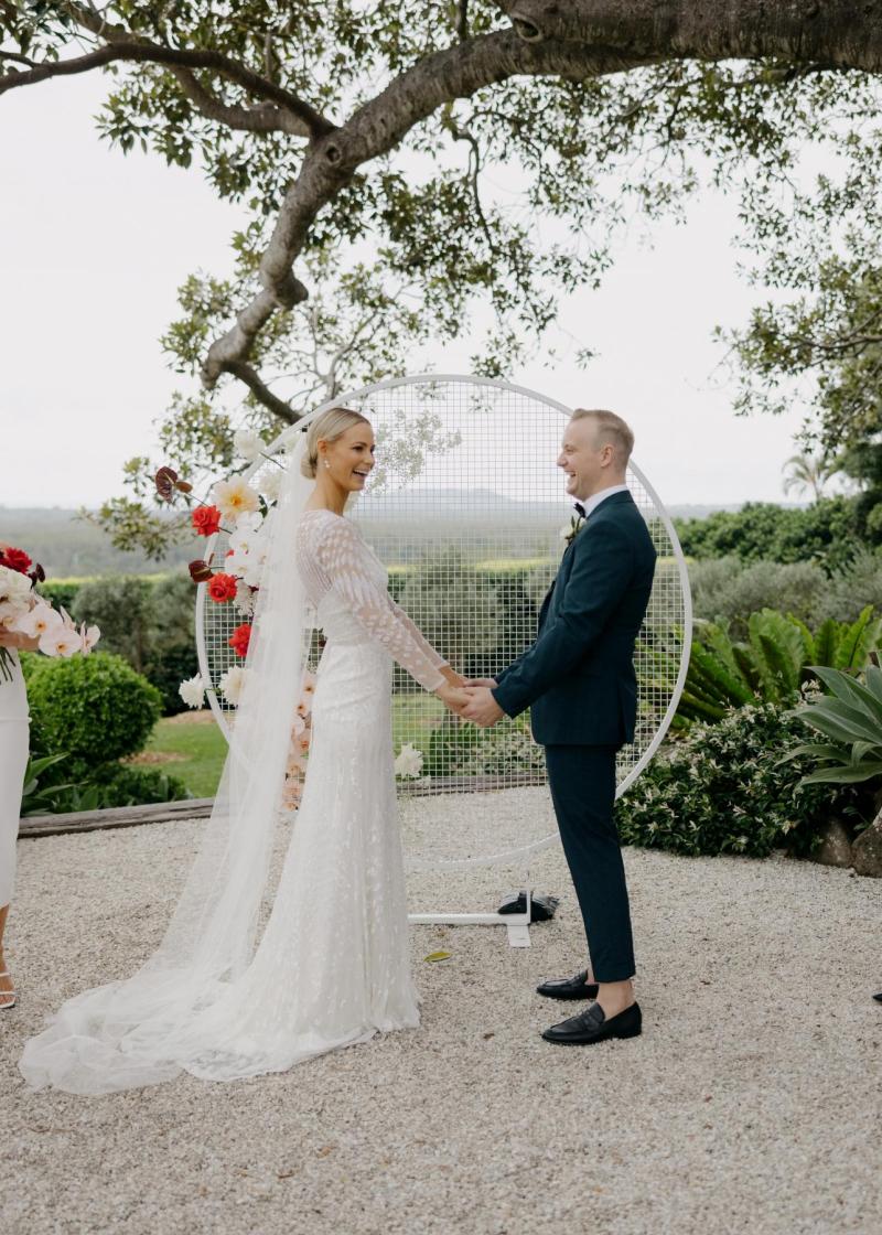 KWH real bride Taylor and Kalen standing in front of their circular wedding alter. She wears the ivory beaded Lexie gown.