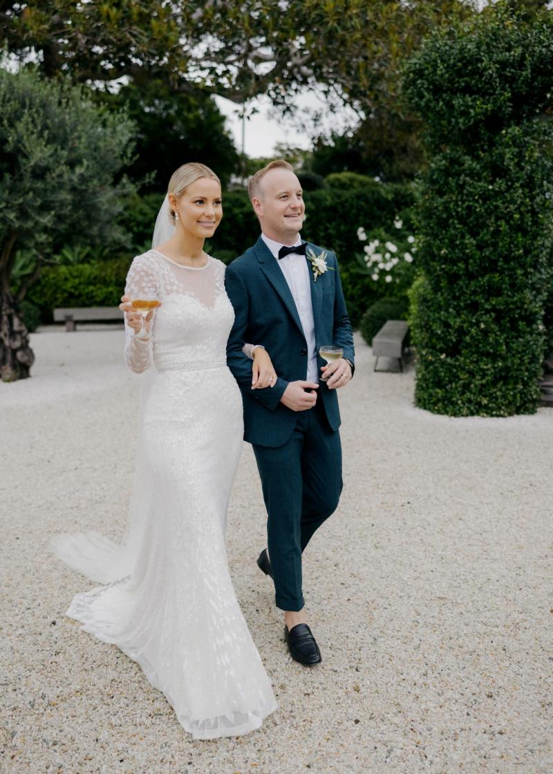 KWH real bride Taylor walking in her sweetheart neckline Lexie wedding dress with a drink in her hand.