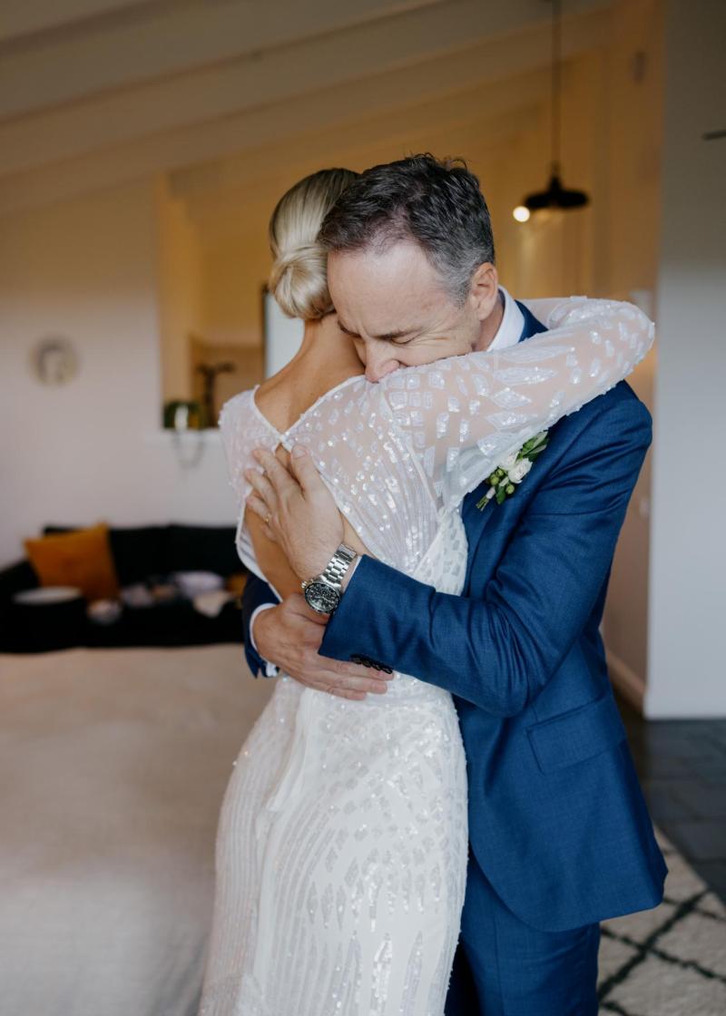 KWH real bride holding a glass in her bridal robe with wedding date embrodiered on the sleeve.