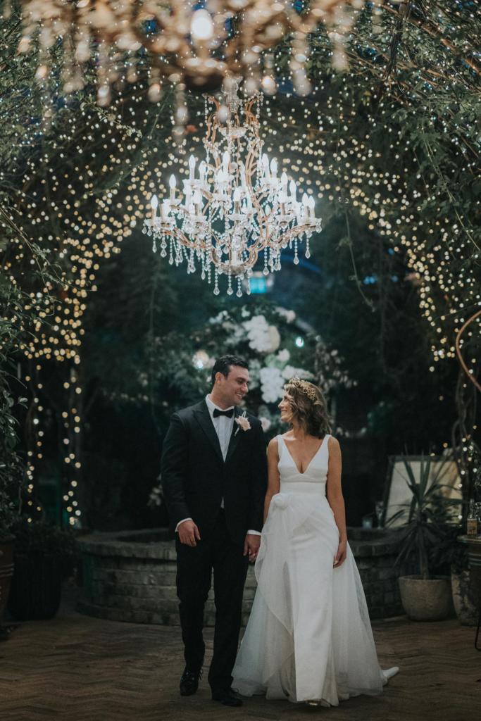 KWH real bride Talia and Phil walking below a gorgeous chandelier. She wore the aline Aisha wedding dress with fitted underlay