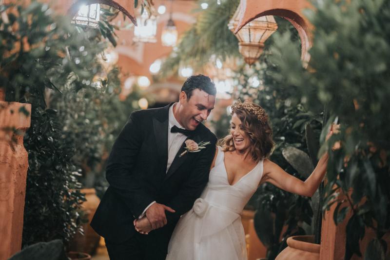 KWH real bride Talia standing under a neon sign at her reception. She wears the modern Aisha wedding dress with leg split in her aline skirt.