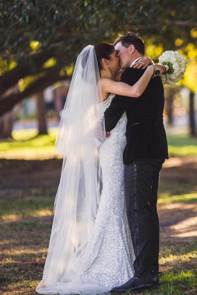 KWH real bride Ash kissing Chris under the trees. She wears the breathtaking Anya wedding dress with uniform sequins.