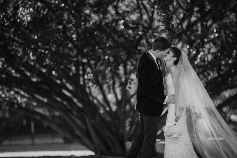 b&W photo of KWH real bride Ash kissing Chris under the trees. She wears the simple Anya wedding dress with sequins.