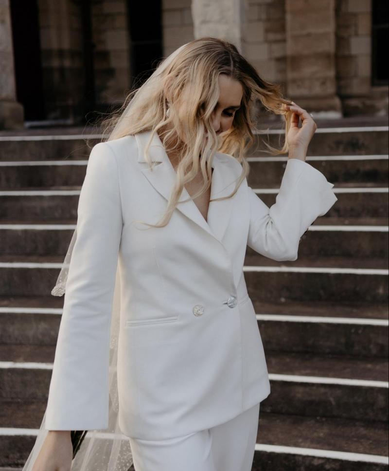 KWH real bride Demi walking up the church steps to her modern elopement. She wears the ivory Charlie Danielle bridal suit.