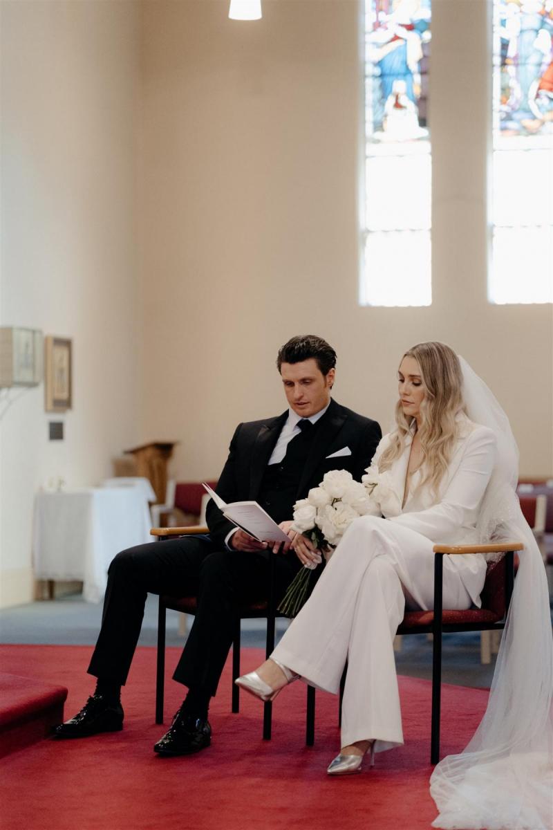 KWH real bride Demi and James sit down at their chatholic wedding ceremony. She wears the ivory Charlie Danielle bridal suit