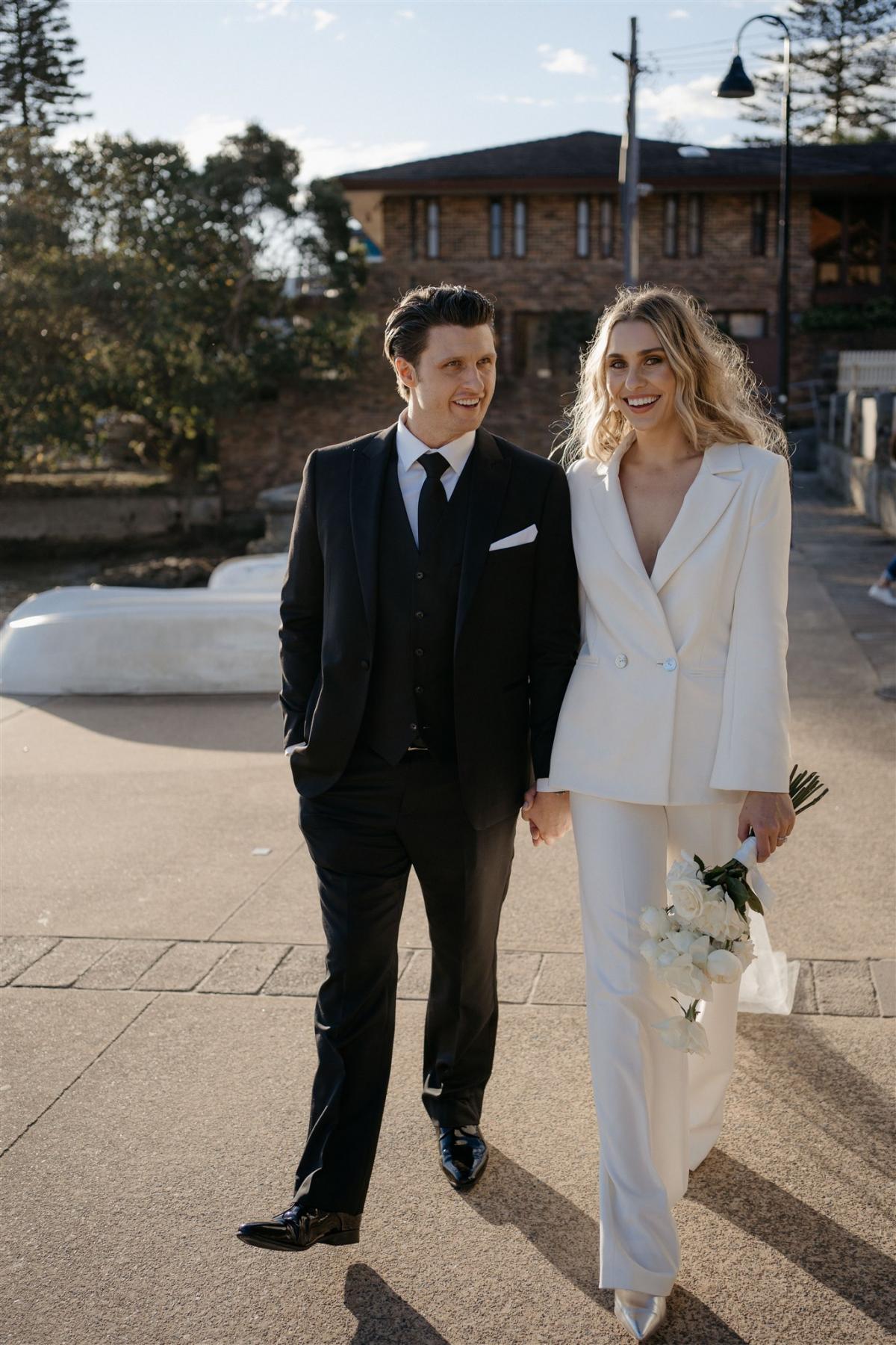 KWH real bride Demi walks with her new husband James along the Sydney Harbour in her minimalist Charlie Danielle bridal suit.
