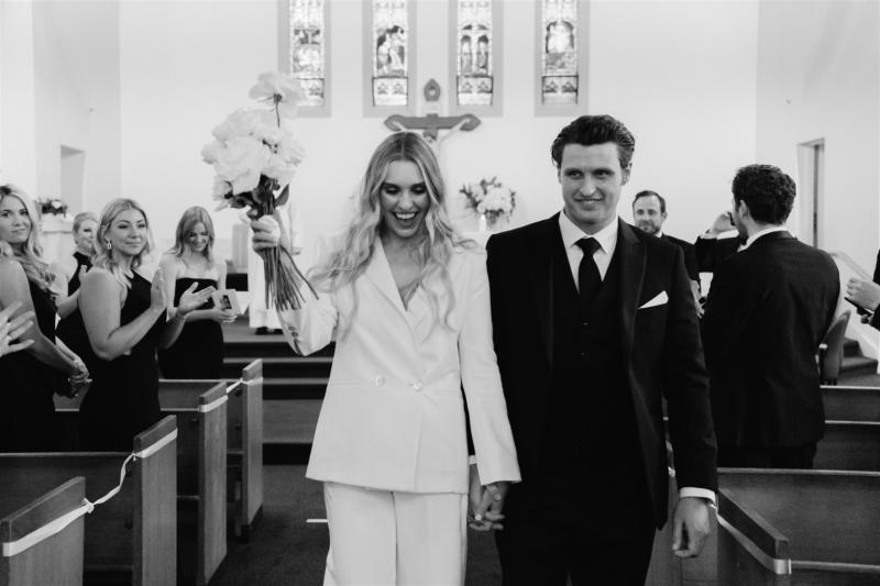 KWH real bride Demi and James walk down the aisle after exchanging vows. She wears the modern Charlie Danielle bridal suit to her elopement.