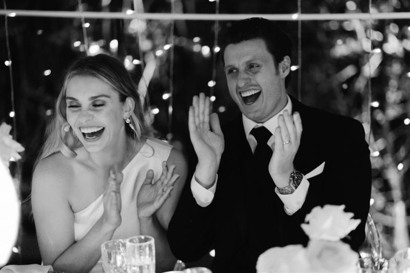 BW image of KWH real bride Demi and James laughing at their reception. She wears the modern Charlie Danielle bridal suit.