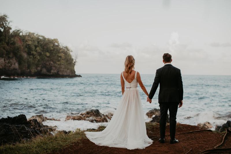 KWH real bride Jana and Garret stand on the shores of Hawaii after their elopement. She dons the two piece Erin and Lea set with aline skirt and crepe bodice.