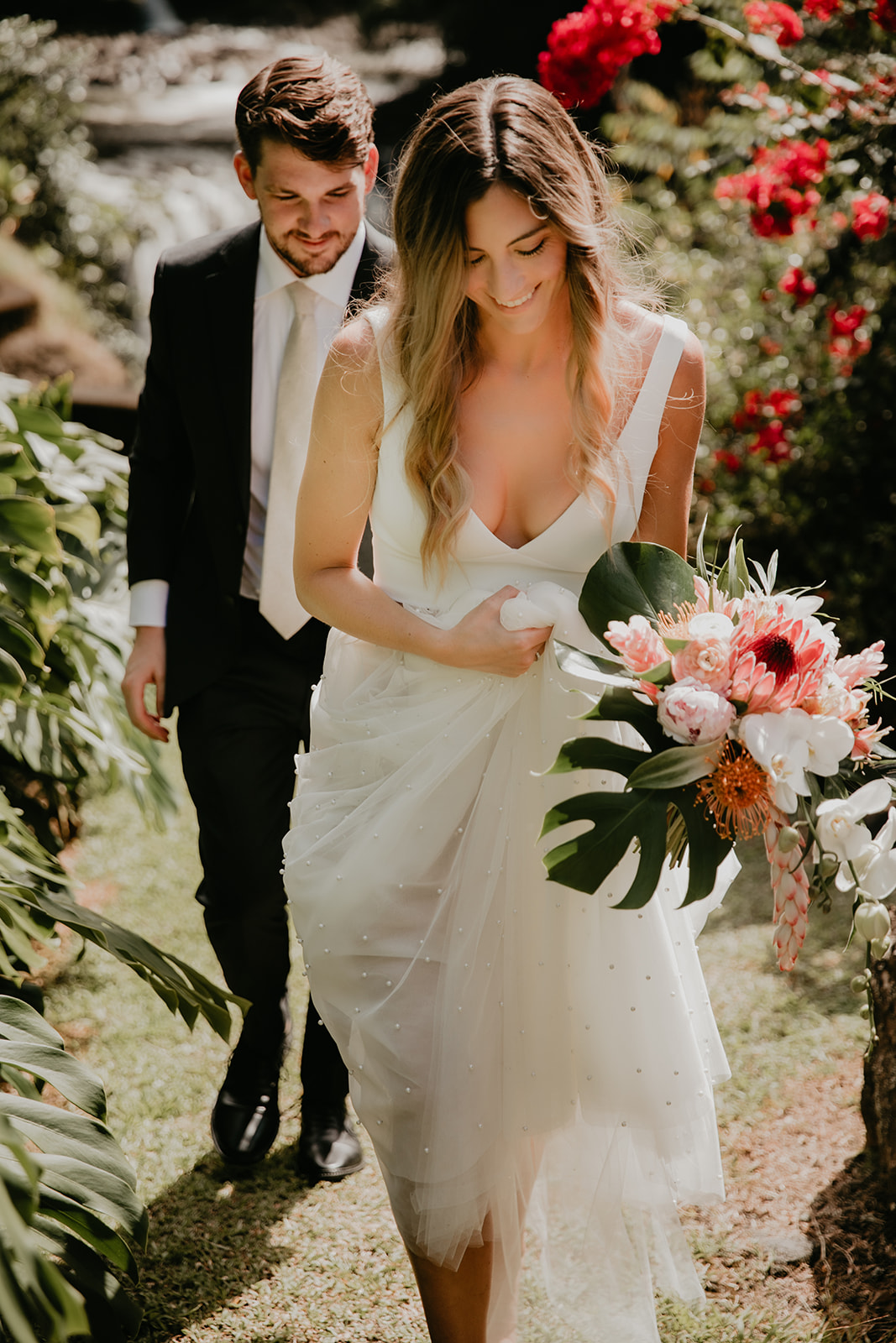 KWH real bride Jana walking up a hill with Garret trailing behind. She wears the comfortable Erin and Lea wedding dress made out of two seperate pieces.