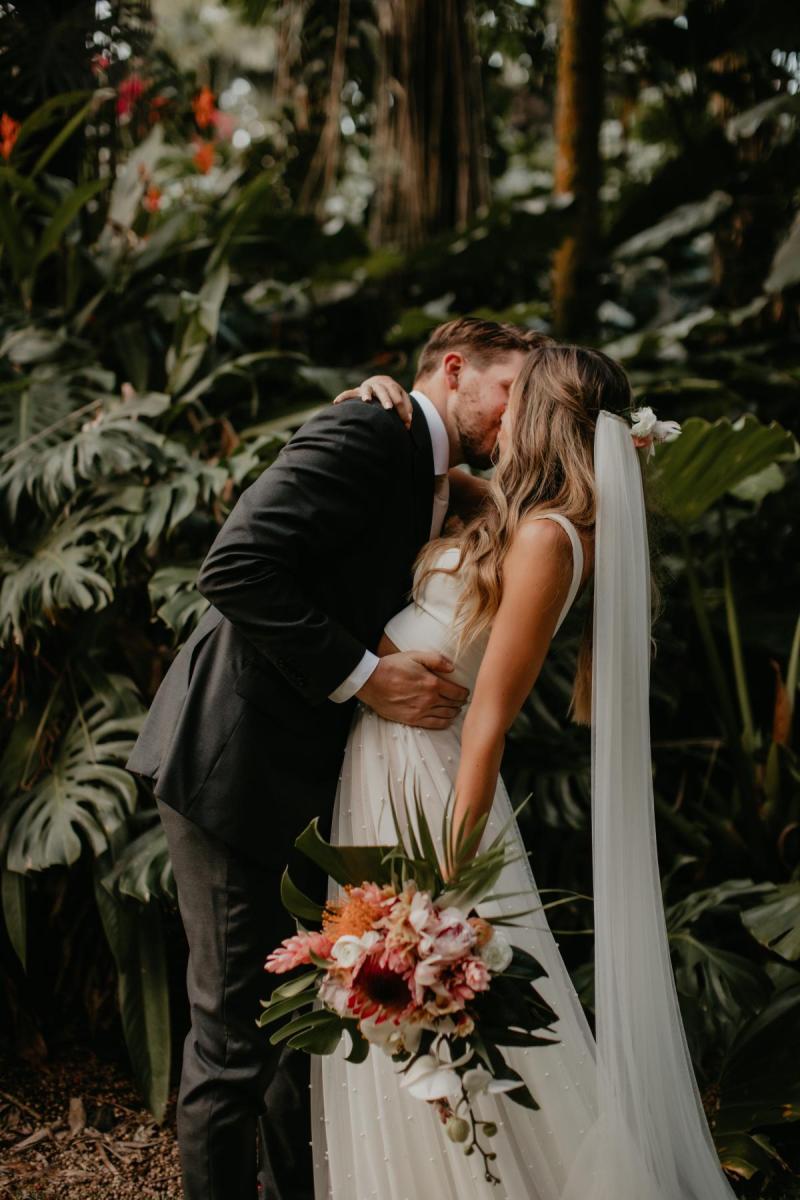 KWH real bride Jana and Garret looking at their matching rings. She wears the effortless Erin and Lea two piece wedding dress with pearl details.