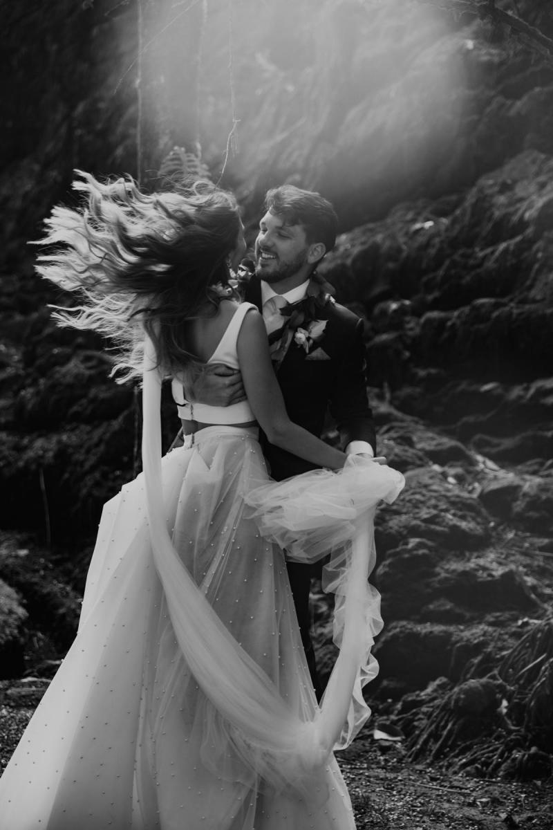 B&W photo of KWH real bride Jana and Garret dancing in the Hawaiian rainforest at their small elopement. She wears the modern Erin and Lea two piece wedding dress with aline skirt and fitted bodice.