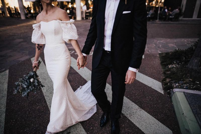 Upclose image of KWH real bride Tess and Liam crossing the street as she wears her simple gorgeous Vivienne wedding dress with structured bodice and puff sleeves.