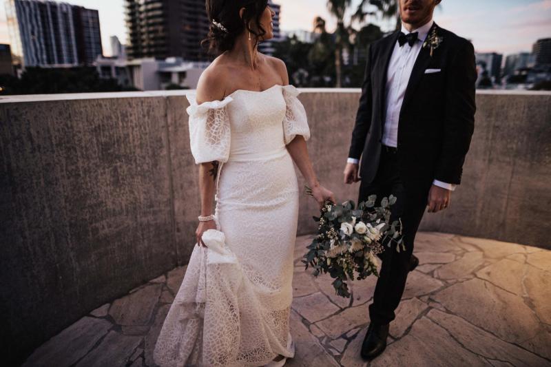 KWH real bride Tess walks with Liam in her delicate lace Vivienne wedding dress with scoop neckline.