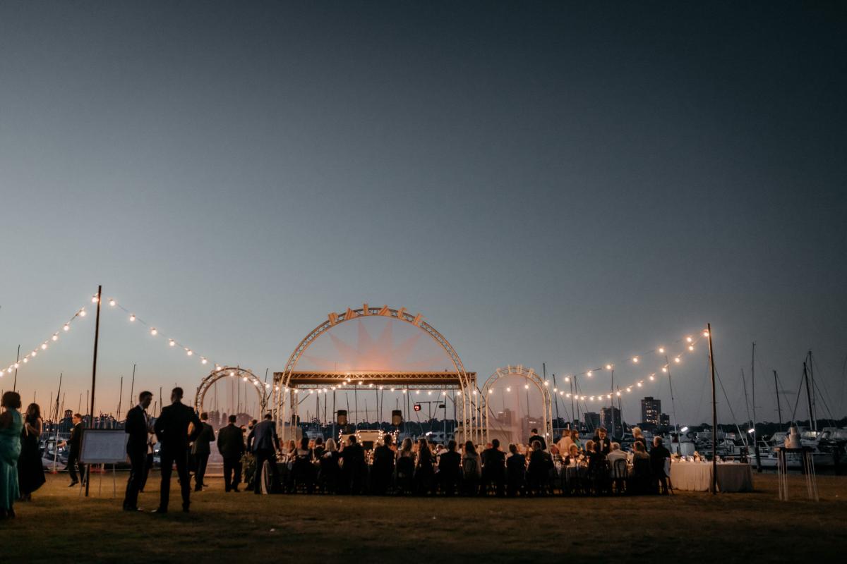 KWH real bride Genevive's outdoor wedding reception with fairy lights and concert stage in the background.