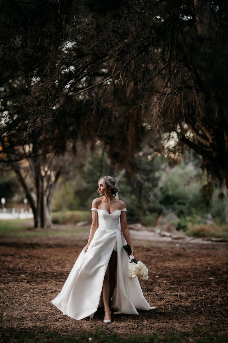 KWH real bride Genevieve walks through the woods with ballgown skirt and high leg split and bustier top.