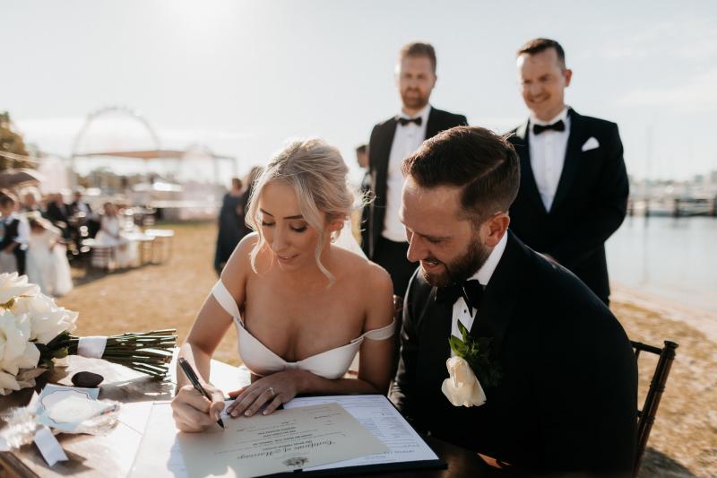 KWH real bride Genevieve and Kyle sign their wedding certificate. She wears the bustier Black Camille wedding dress.