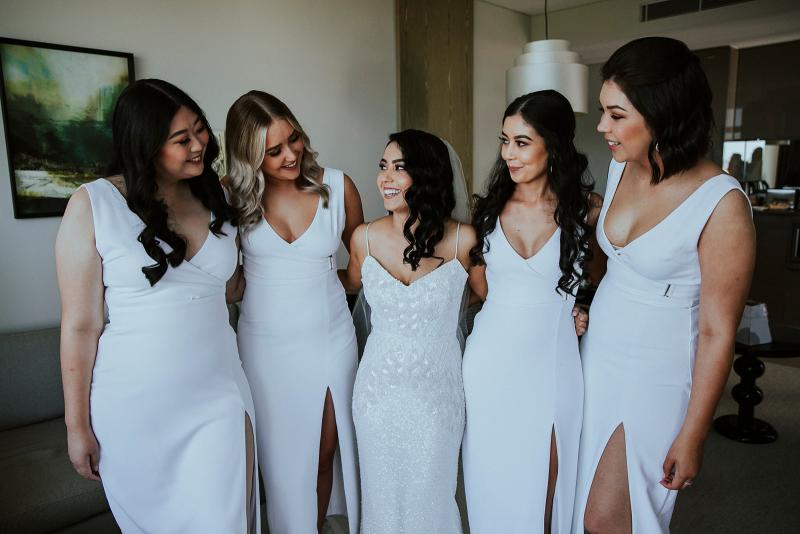 KWH real bride Jaz stands with her bride'smaids who are wearing white. She wears the sparkly Darcy gown, a fit and flare sequin wedding dress
