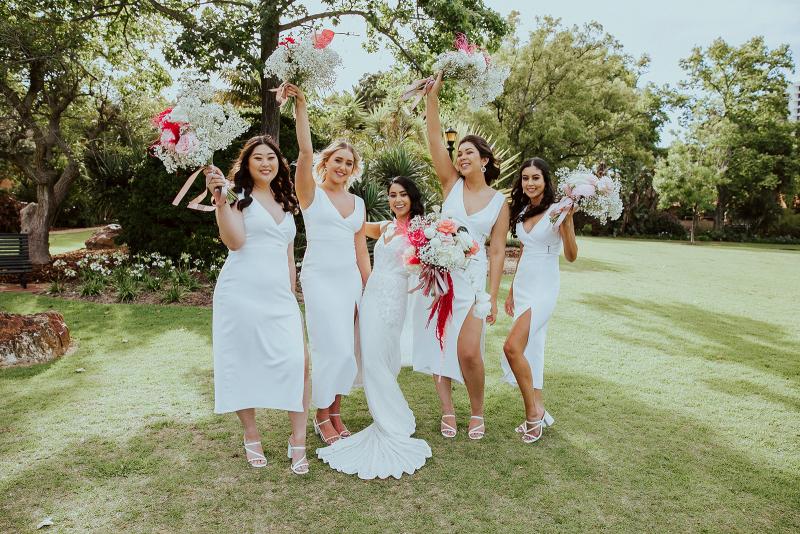 KWH real bride Jaz and her bridesmaids throwing up their bouquets in excitement. She wears the ivory Darcy gown, a hand-beaded fit and flare sexy wedding dress.
