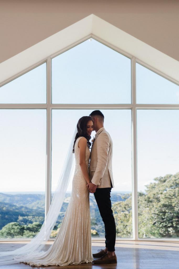 KWH real bride Georgie snuggles into Mikey at the alter. She wears the Fontanne gown, a low back beaded wedding dress.