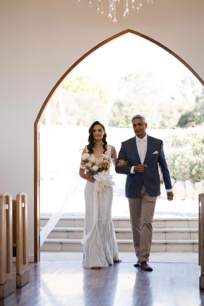 KWH real bride Georgie walks down with her father. She wears The Fontanne gown, art deco beaded fit and flare wedding dress.
