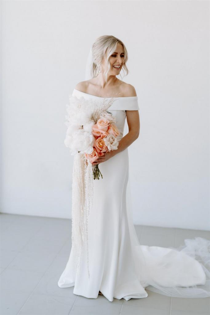 KWH real bride Shelley stands in her classic Lauren wedding dress with keyhole back and off the sholder sleeve.