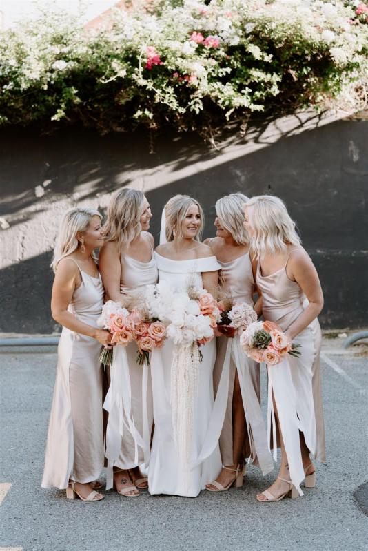 KWH real bride Shelley stands with her bridesmaids who are wearing champagne coloured silk dresses. She wears the simple Lauren wedding dress.