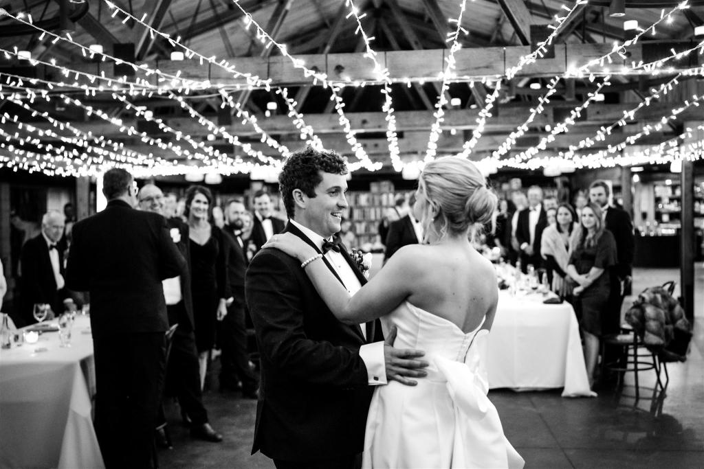 B&W image of KWH real bride Annabelle and Will sharing their first dance under the fairy lights. She wears the timeless Jacqueline Melanie gown, a modern bridal balllgown